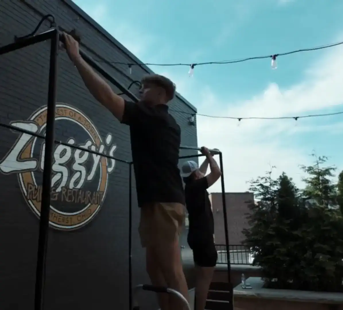 Two crew members setting up a portable golf simulator frame on Ziggy's patio in Amherst, Ohio