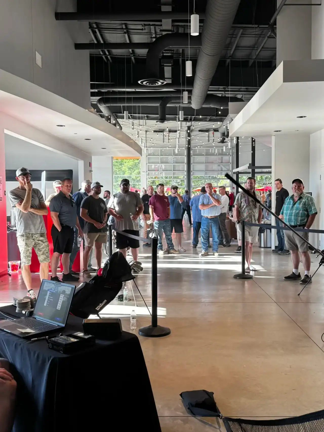 Guests lined up to try a portable golf simulator setup at an indoor corporate event