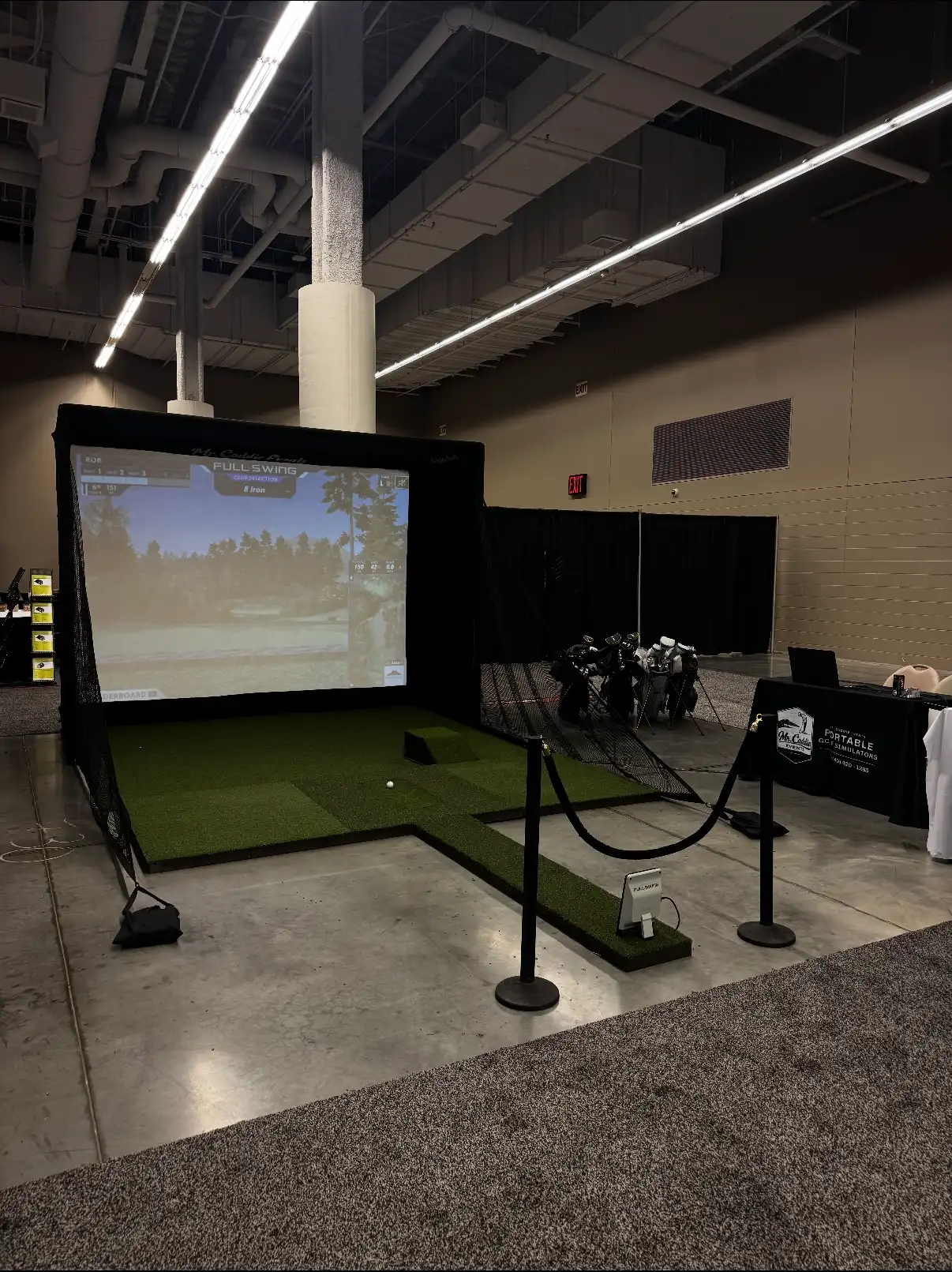 Mr. Caddie Events portable golf simulator set up at a trade show with a Full Swing launch monitor and branded table