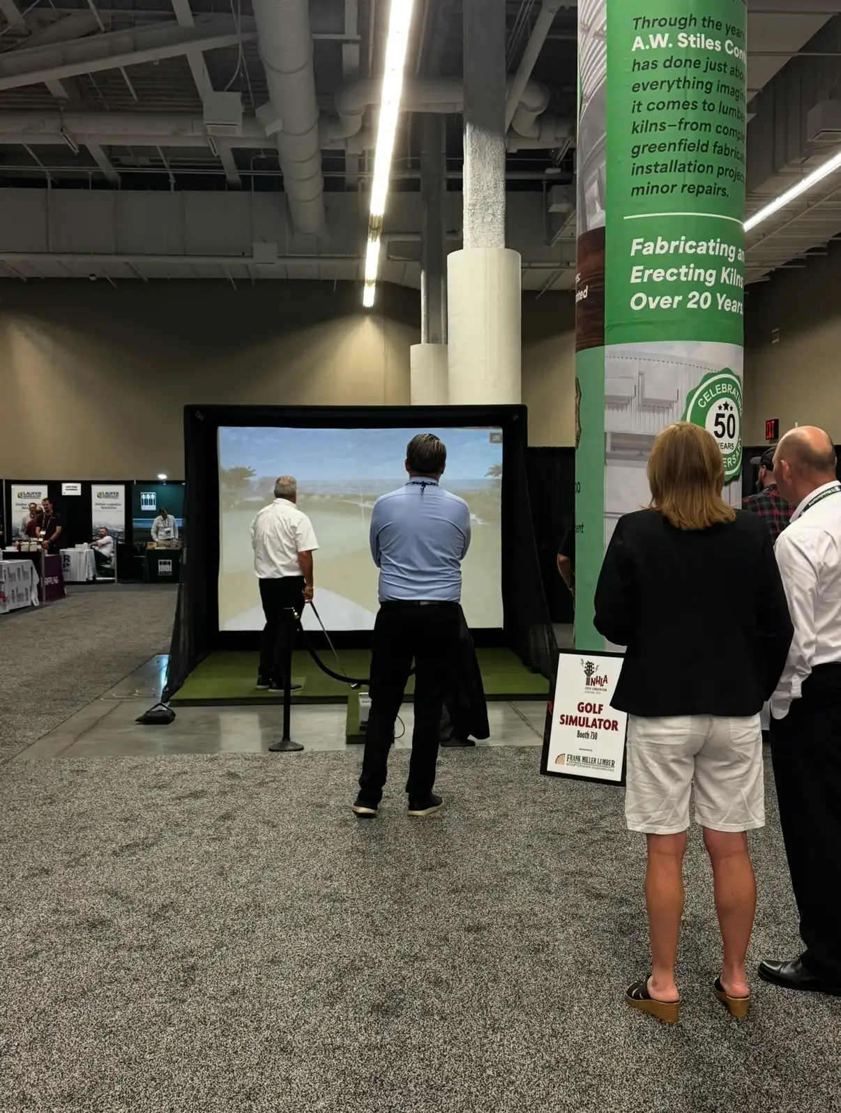 Guest taking a shot on the Mr. Caddie Events golf simulator at a trade show while others watch