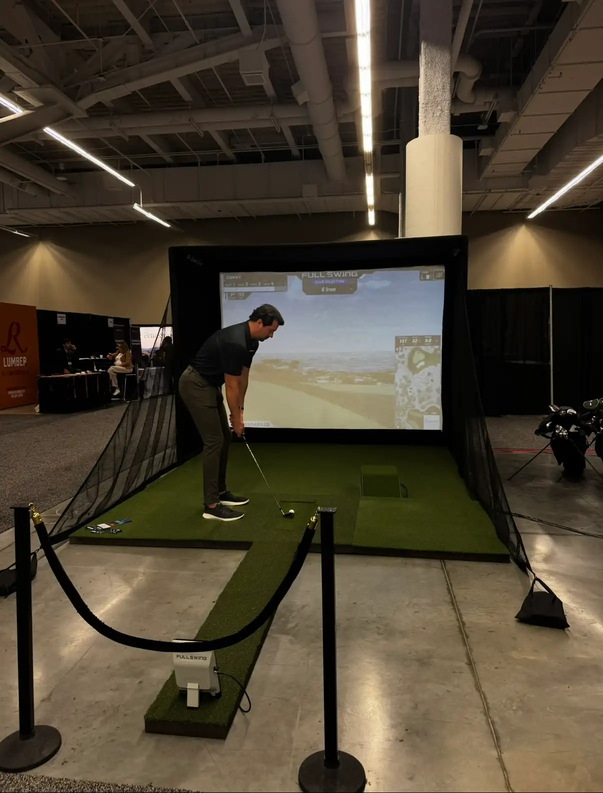 Guest addressing the ball on the Mr. Caddie Events golf simulator at a trade show
