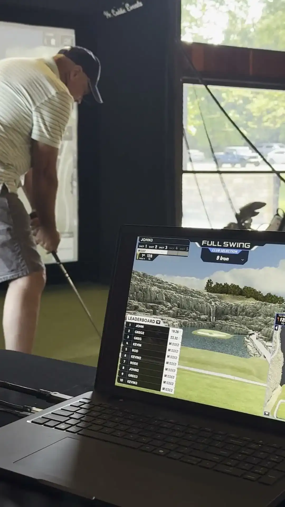 Golfer finishing full swing with 8 iron on CaddieShack indoor golf simulator